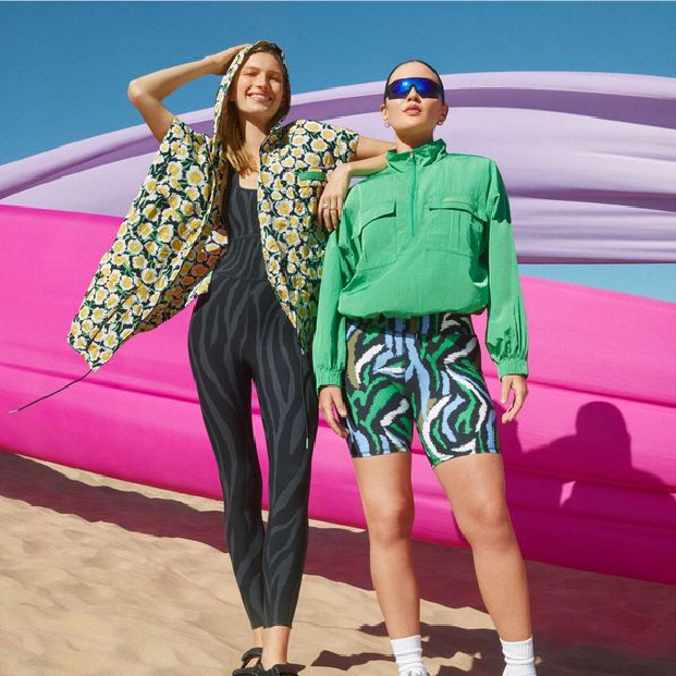 Two people pose in green and yellow floral and geometric-patterned athleisure.