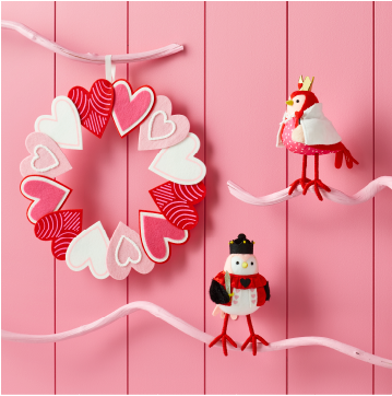 A wreath of felt hearts and two cute decorative birds on white branches.