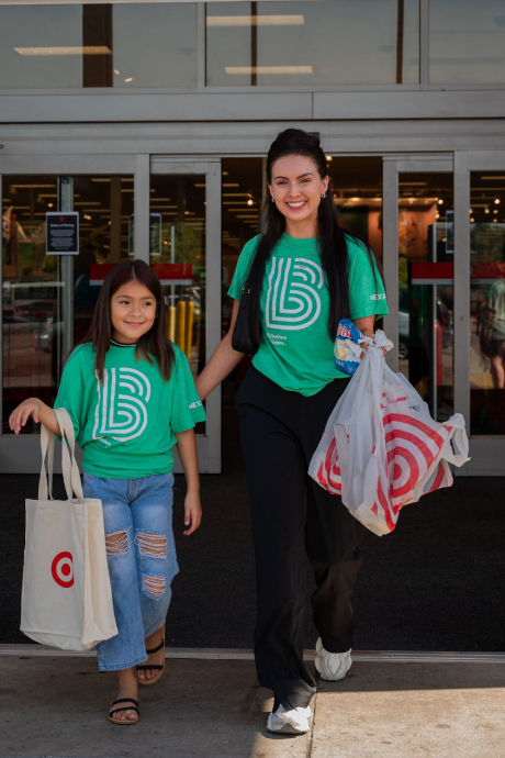 Two people, one a Big and the other a Little, leave Target with their shopping bags after a back-to-school event.