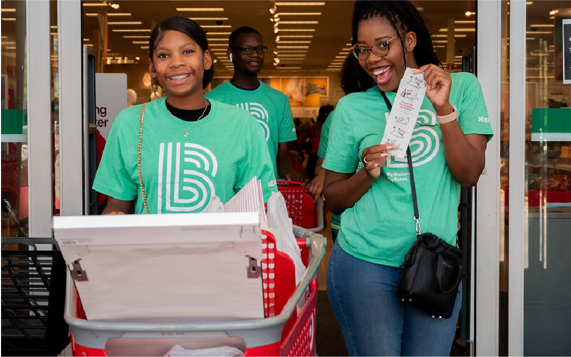 A Big and Little pair leave a Target store with a cart and a receipt.