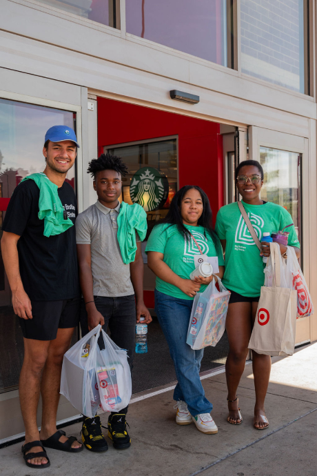 Four people, two Bigs and two Littles, pose together outside a Target store holding their new back-to-school purchases.