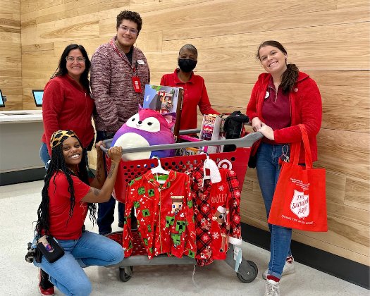 a group of people posing for a photo with a cart of candy