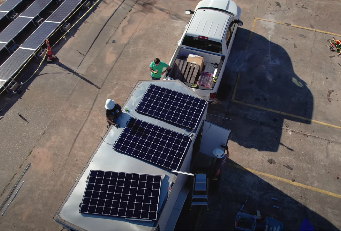 Solar panels loaded on a trailer connected to a truck.