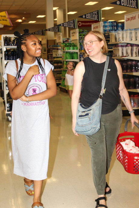 A Big and a Little walk through the Target aisles, chatting and smiling during a back-to-school shopping event.