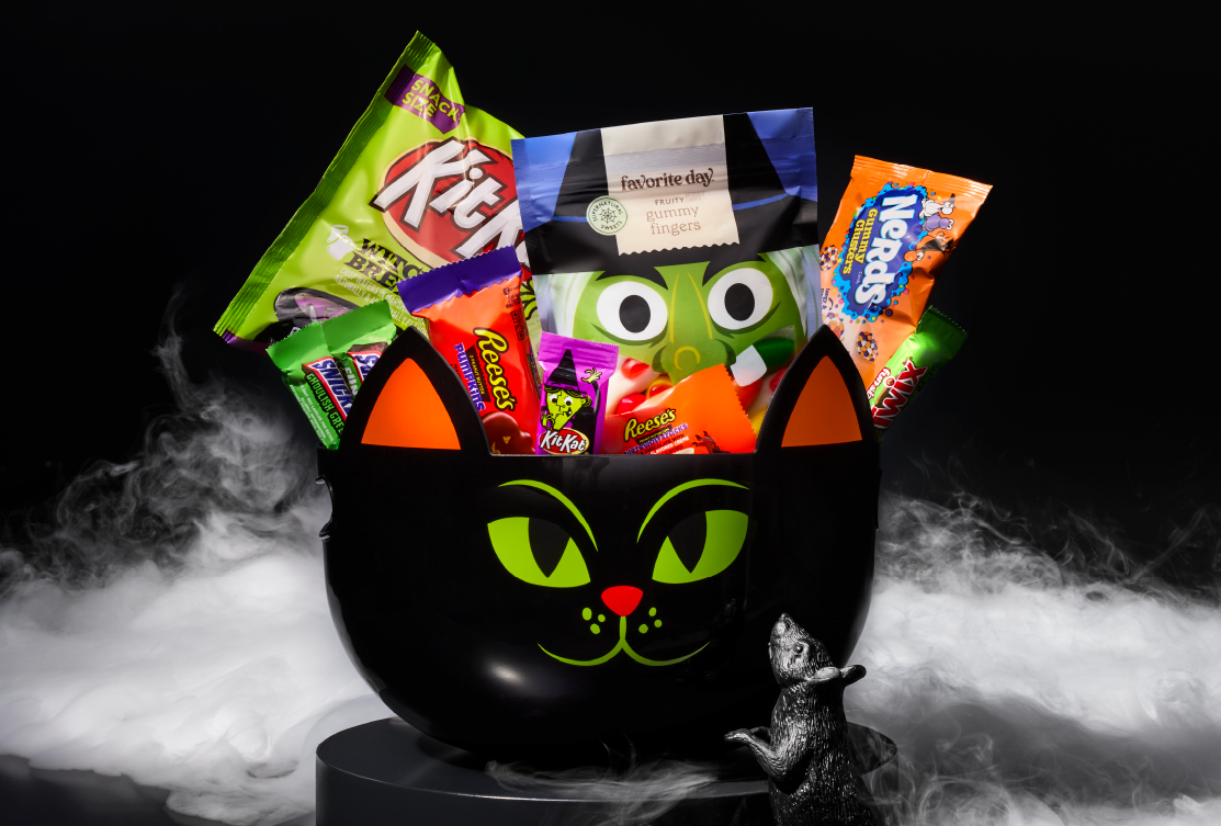 A black serving bowl that looks like a cat filled with Halloween candy.