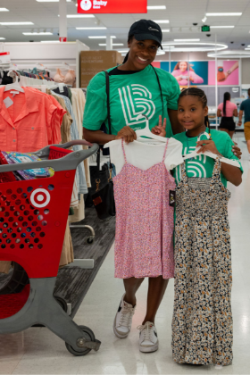 Two people, one a Big and the other a Little, hold up dresses they picked out together during a back-to-school shopping event at Target.